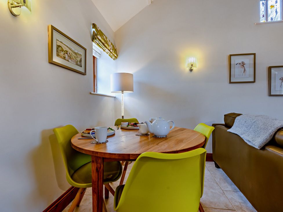 A dining room with a table and chairs at Barley Park in Marhamchurch