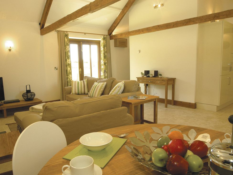 A living room with a sofa and dining area at Barley Park in Marhamchurch