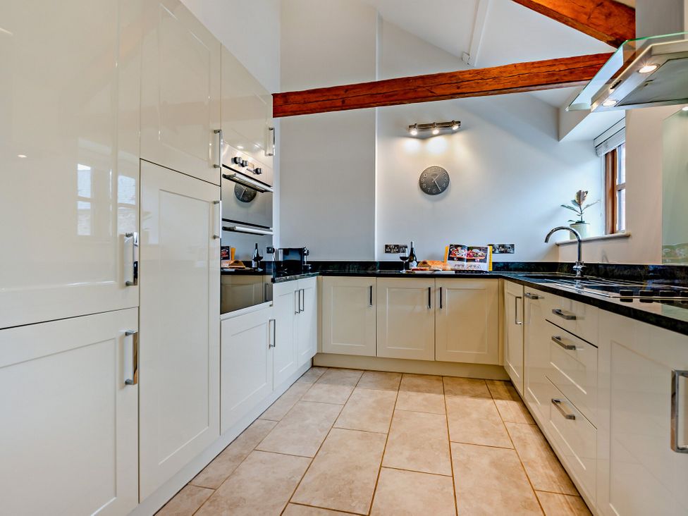 A kitchen with cabinets, sink, and oven at Barley Park in Marhamchurch