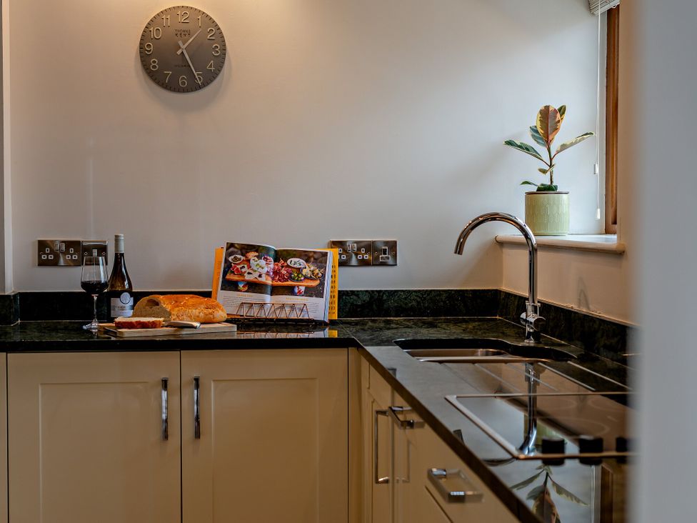 A kitchen with a clock and countertop items at Barley Park in Marhamchurch