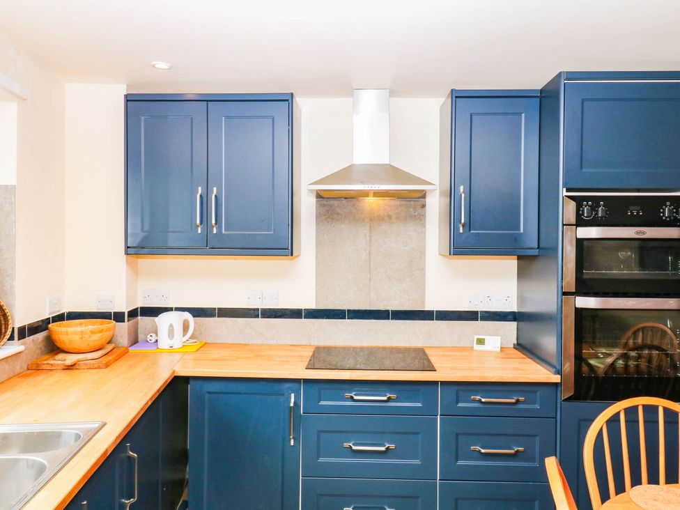 A kitchen with blue cabinets and wooden countertop at The Gables in Teignmouth