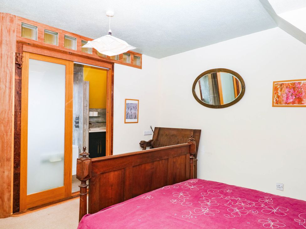 A bedroom with a wooden bed and a mirror at The Gables in Teignmouth