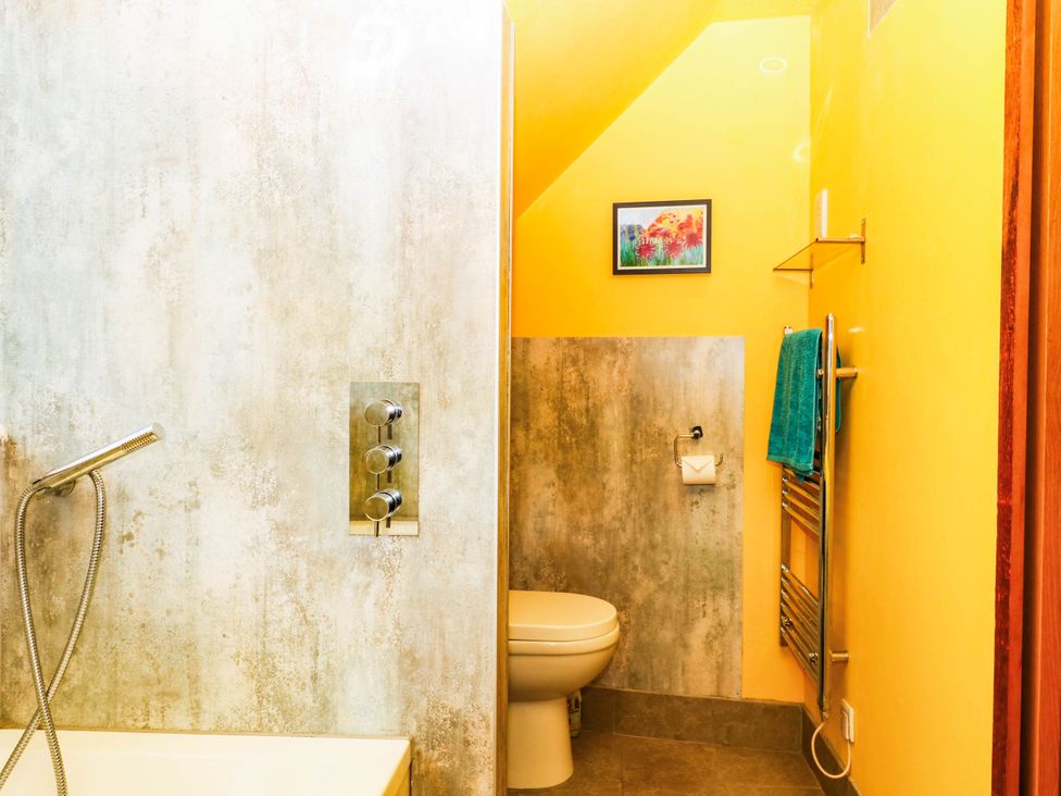 A bathroom with a bathtub, toilet, and towel rack at The Gables in Teignmouth