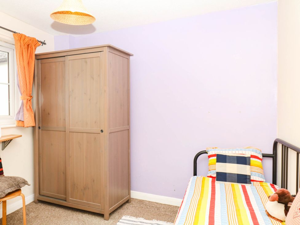 A bedroom with a wardrobe, bed, and window at The Gables in Teignmouth