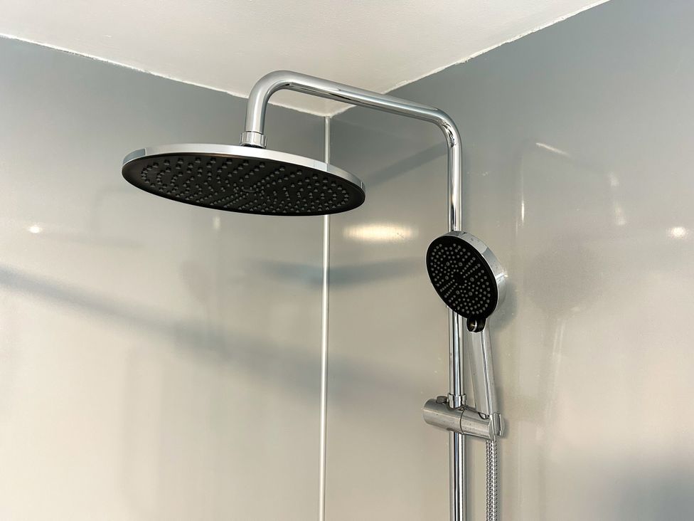 A shower head and handheld shower head in a bathroom at Scamnel in Eccleshall