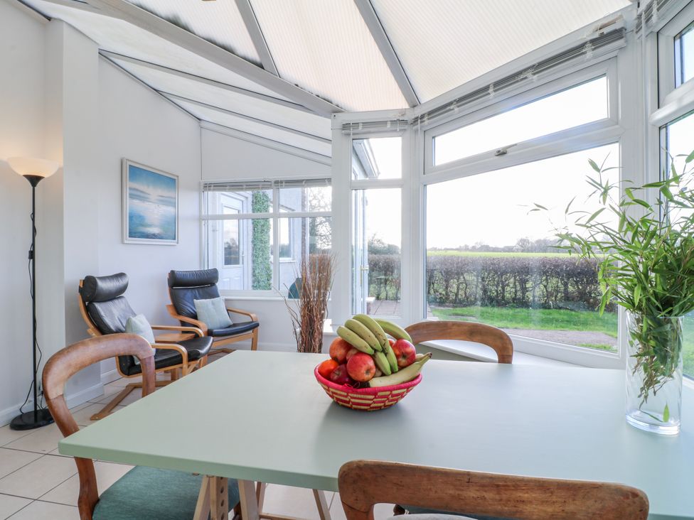 A conservatory with a table and chairs at Scamnel in Eccleshall