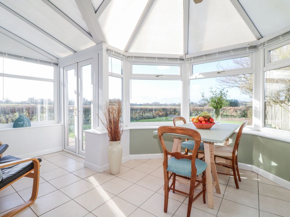 A conservatory with a table and chairs at Scamnel, Eccleshall