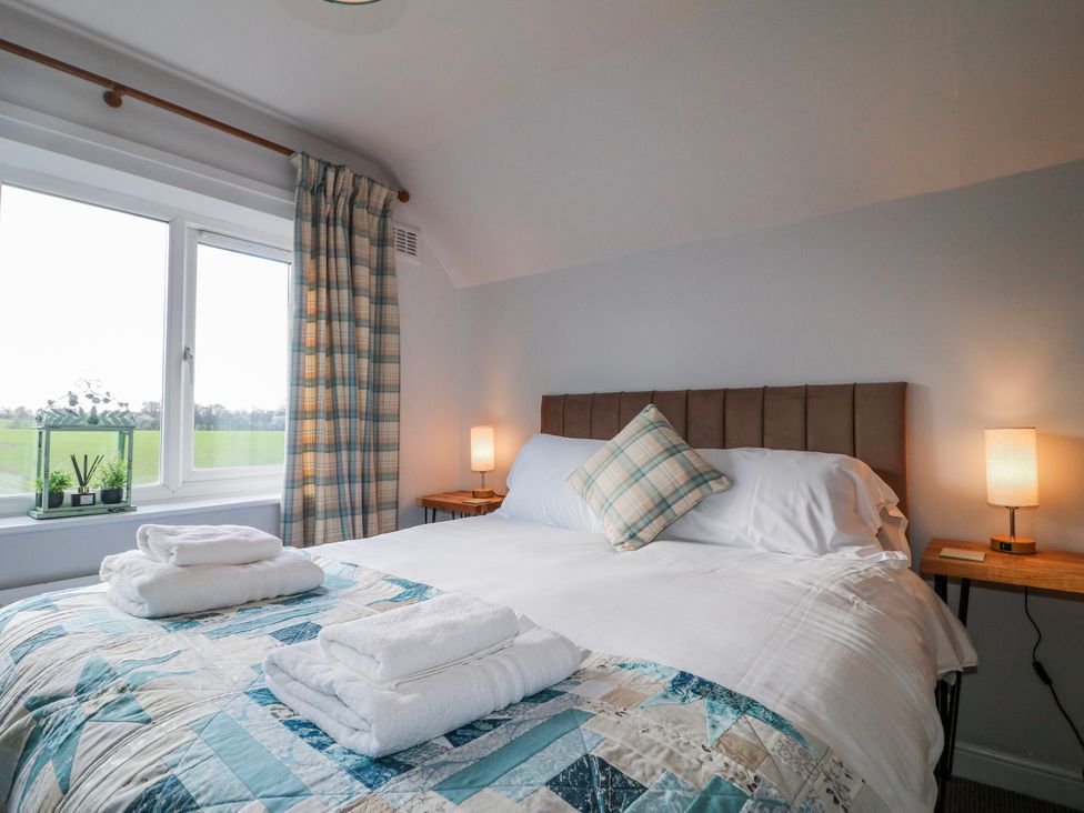 A bedroom with a bed and plant by the window at Scamnel in Eccleshall