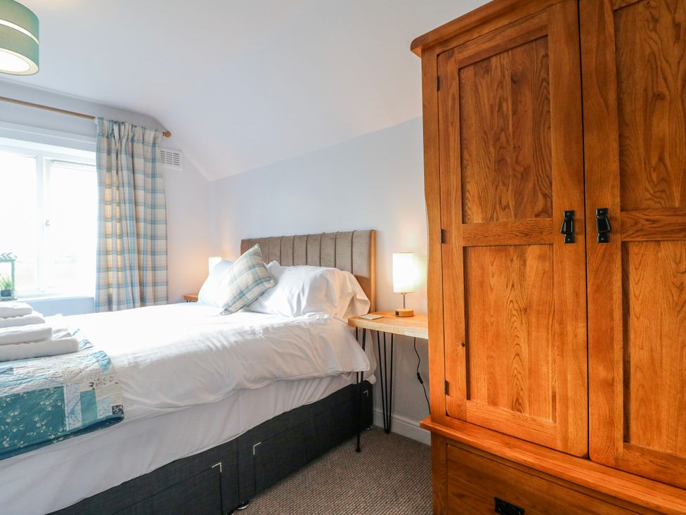 A bedroom with a bed and wooden wardrobe at Scamnel in Eccleshall