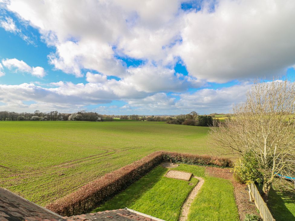 A garden with a hedge and trees in view of fields at Scamnel Eccleshall