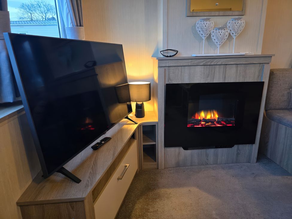 A living room with a TV and electric fireplace at Brynowen Holiday Park - Holiday Accommodation 22432, Borth