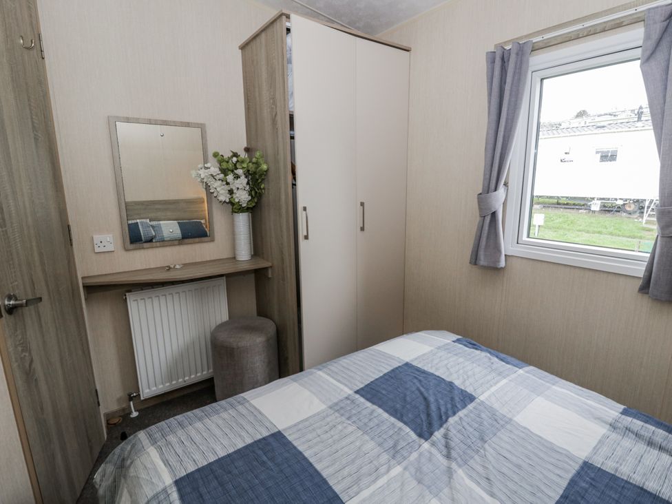 A bedroom with a bed, mirror, wardrobe, and window at Brynowen Holiday Park - Holiday Accommodation 22432, Borth