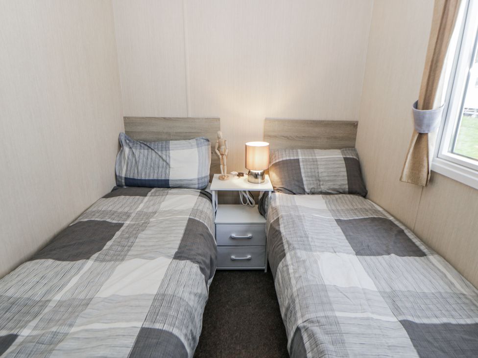A bedroom with two beds and a nightstand at Brynowen Holiday Park - Holiday Accommodation 22432, Borth