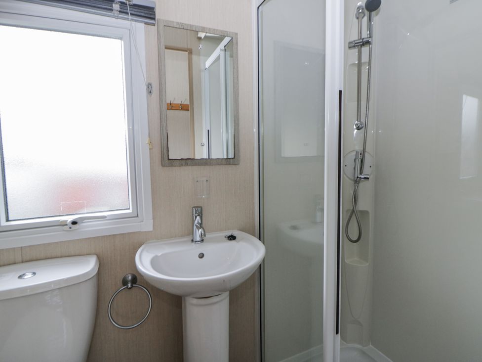 A bathroom with a sink, toilet, shower, and mirror at Brynowen Holiday Park - Holiday Accommodation 22432 Borth