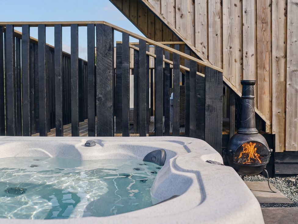 A hot tub and fire pit on a wooden deck at Orka 1.0 Spa (Pet) Dumfries