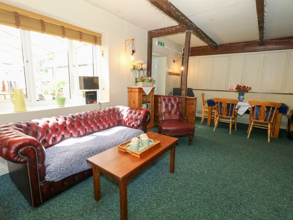 A living room with a sofa, table, and chairs at The Old Barn in Stourton Caundle near Stalbridge