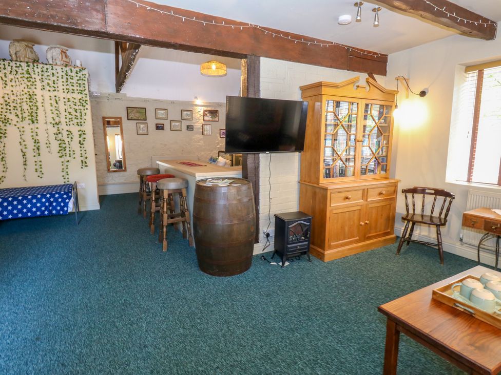 A living room with a TV, cabinet, and barrel at The Old Barn in Stourton Caundle near Stalbridge
