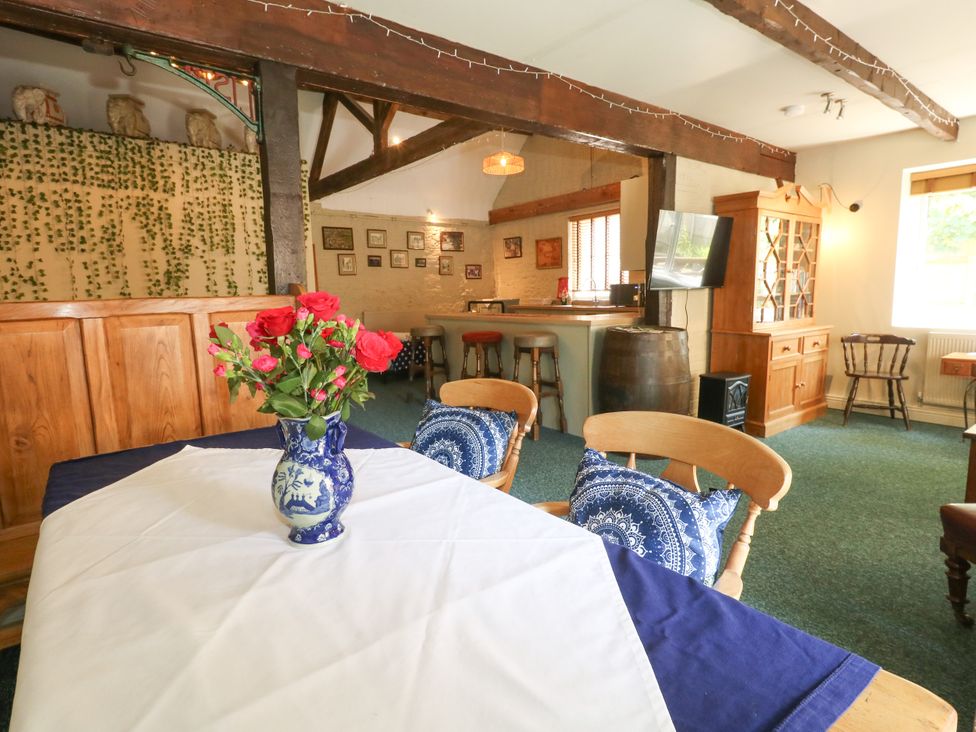 A dining room with a table, chairs, and flowers at The Old Barn in Stourton Caundle near Stalbridge