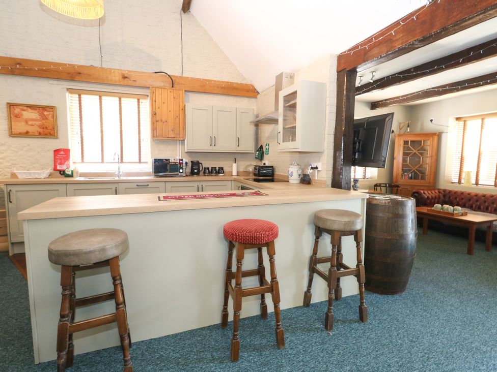 A kitchen with bar stools and cabinets at The Old Barn in Stourton Caundle near Stalbridge