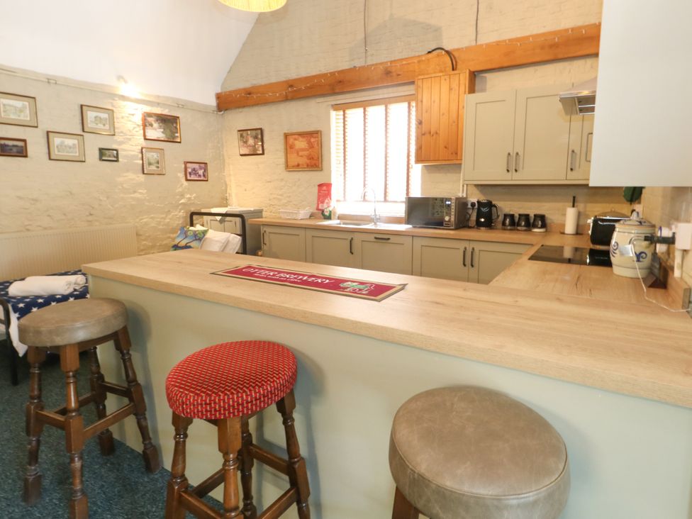 A kitchen with bar stools and cabinets at The Old Barn in Stourton Caundle near Stalbridge