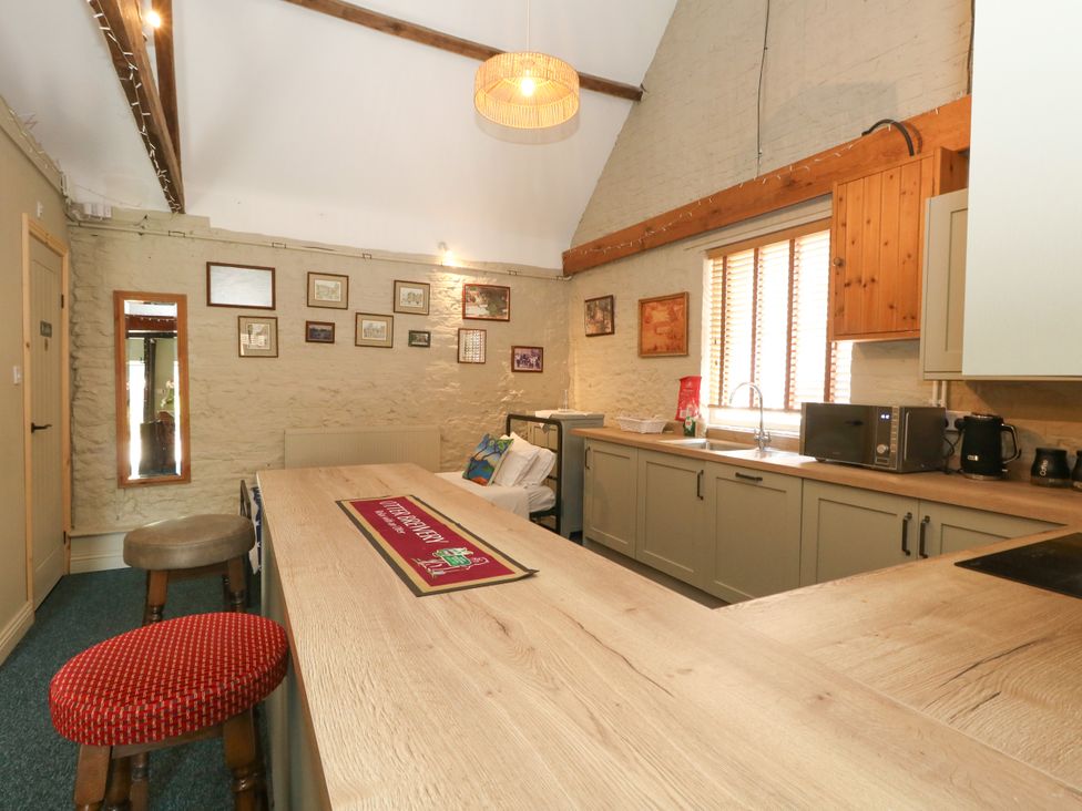 A kitchen with a table and bar stools at The Old Barn in Stourton Caundle near Stalbridge