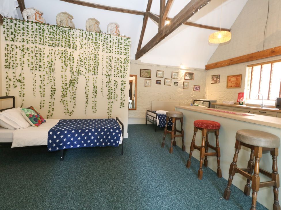 An open plan living area with a bed and a bar counter at The Old Barn in Stourton Caundle near Stalbridge