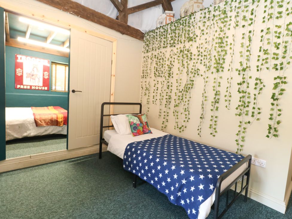 A bedroom with a bed and decorative plants at The Old Barn in Stourton Caundle near Stalbridge