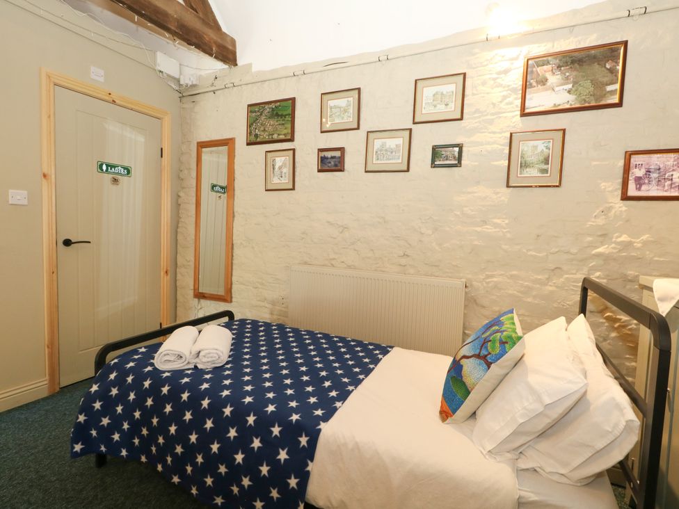 A bedroom with a bed and wall pictures at The Old Barn in Stourton Caundle near Stalbridge