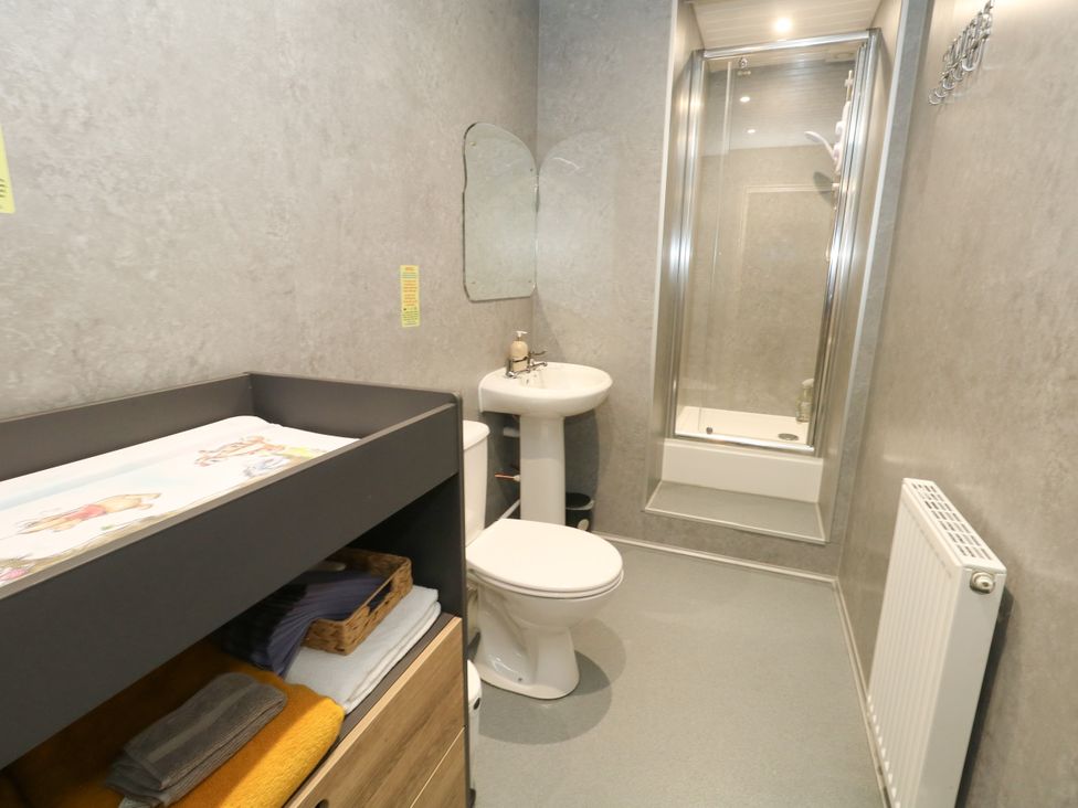 A bathroom with a changing table, sink, shower and toilet at The Old Barn in Stourton Caundle near Stalbridge