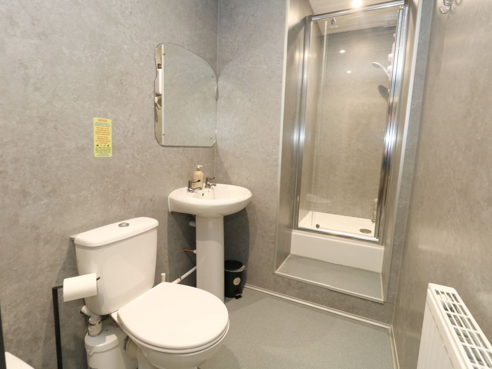 A bathroom with a toilet, washbasin, and shower at The Old Barn in Stourton Caundle near Stalbridge
