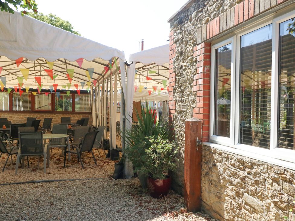 An outdoor area with tables and chairs under a tent at The Old Barn in Stourton Caundle near Stalbridge