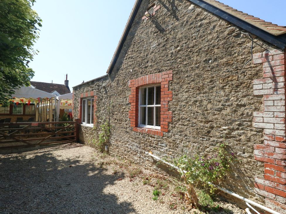 A stone wall with a window and gravel area at The Old Barn in Stourton Caundle near Stalbridge