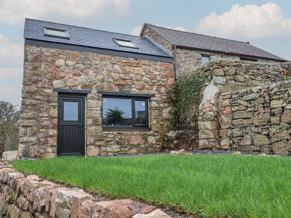 An outdoor view of a stone building and grass at Trigfa Brynsiencyn near Llanfairpwllgwyngyll