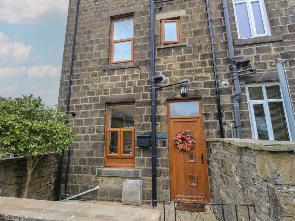 The entrance of a stone house with a wooden door and a window at 11 Bronte Street in Haworth