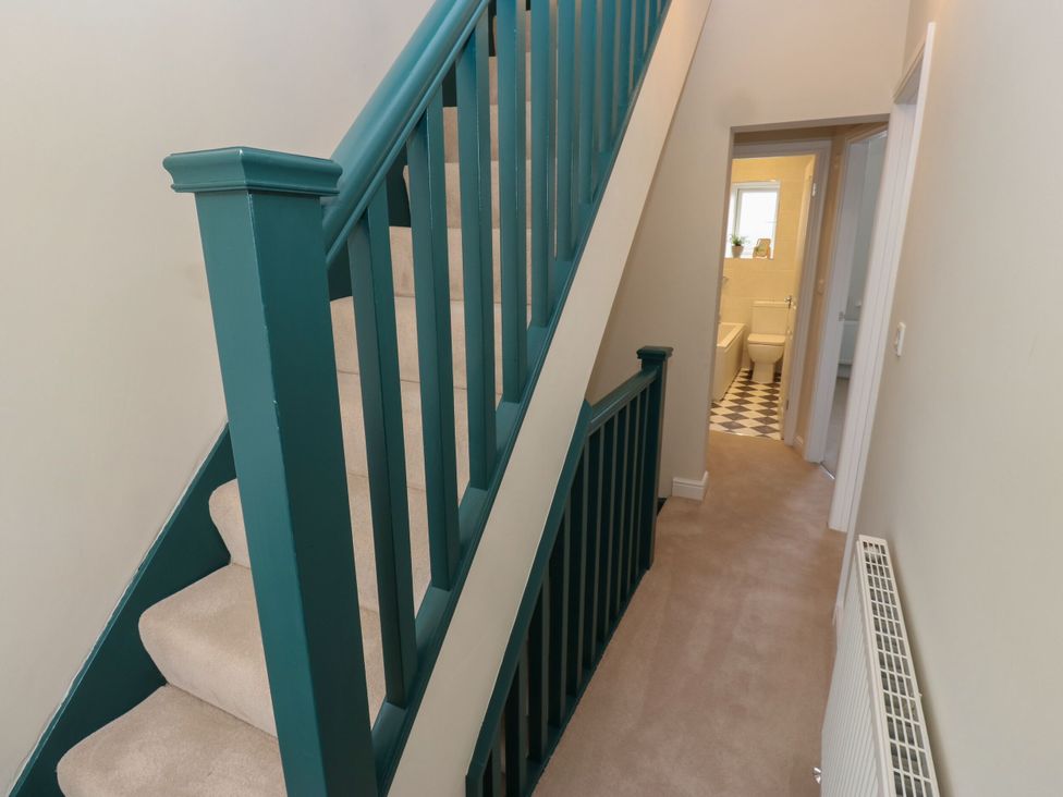 A hallway with a staircase and bathroom door at 11 Bronte Street Haworth