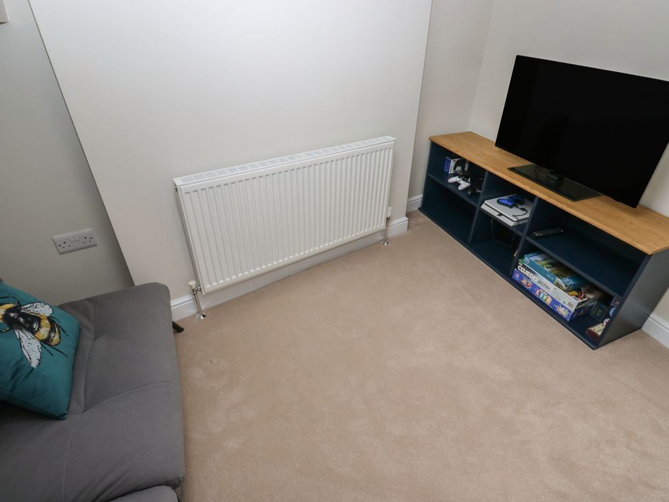 A living room with a sofa, television, and radiator at 11 Bronte Street in Haworth