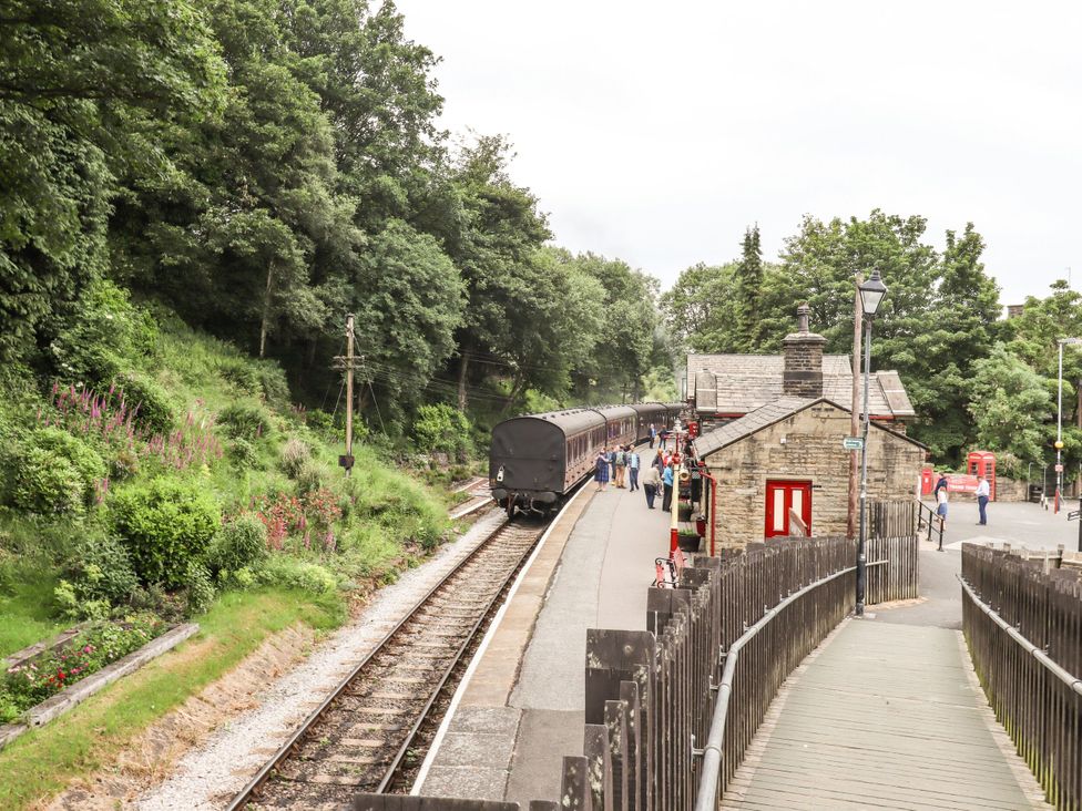 A train at a station with passengers waiting at 11 Bronte Street in Haworth