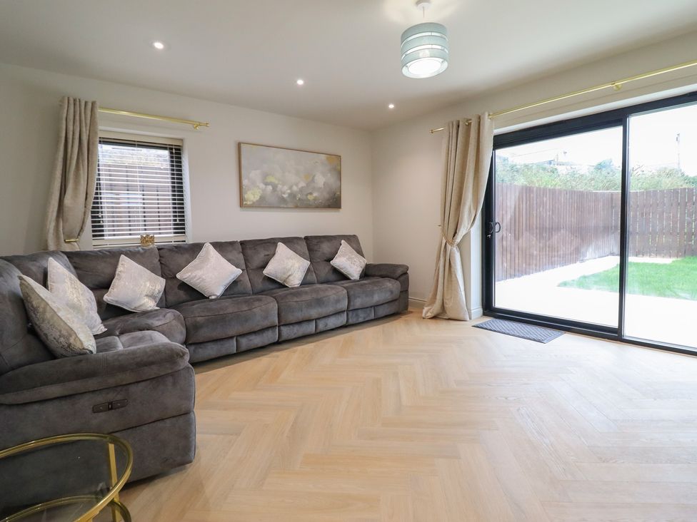 A living room with a sofa and sliding glass door at Pistyll Ddu in Brynsiencyn near Llanfairpwllgwyngyll
