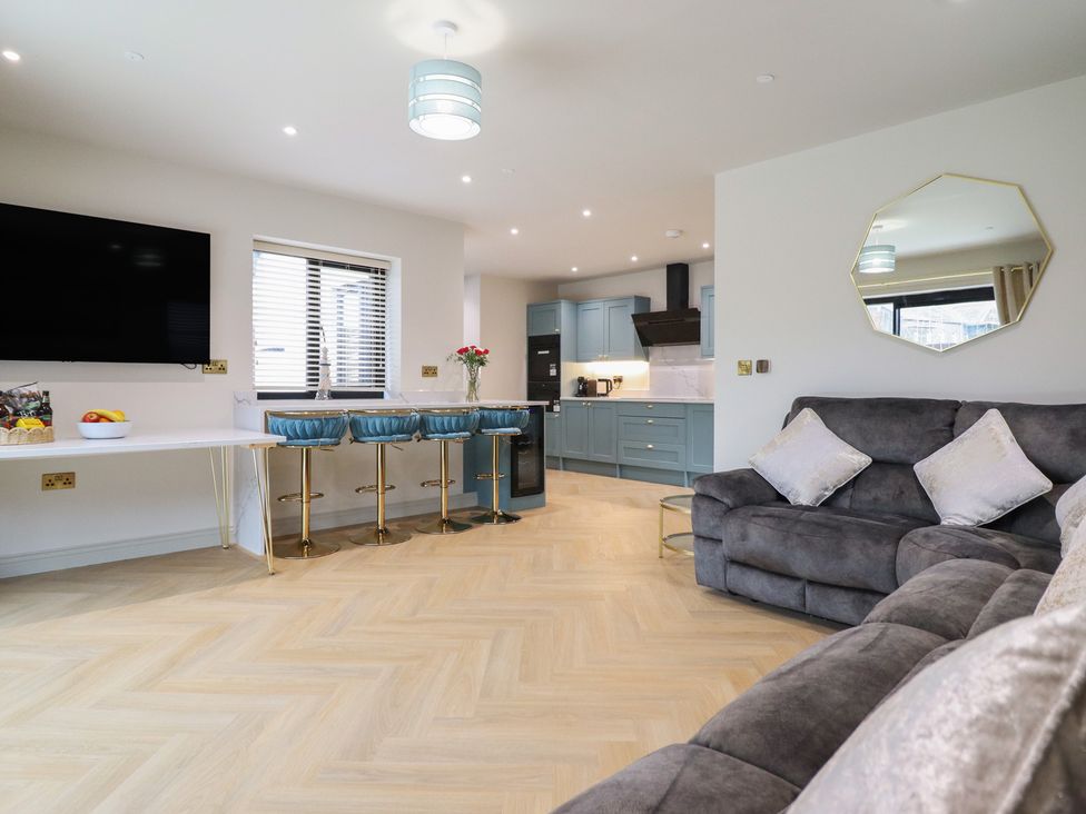 A living room with a television and bar stools at Pistyll Ddu Brynsiencyn near Llanfairpwllgwyngyll