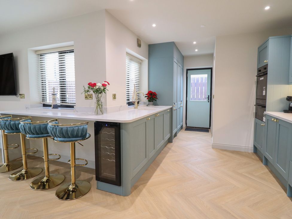 A kitchen with bar stools and a wine cooler at Pistyll Ddu in Brynsiencyn near Llanfairpwllgwyngyll