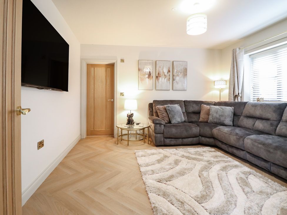 A living room with a large sofa and a television at Pistyll Ddu near Brynsiencyn