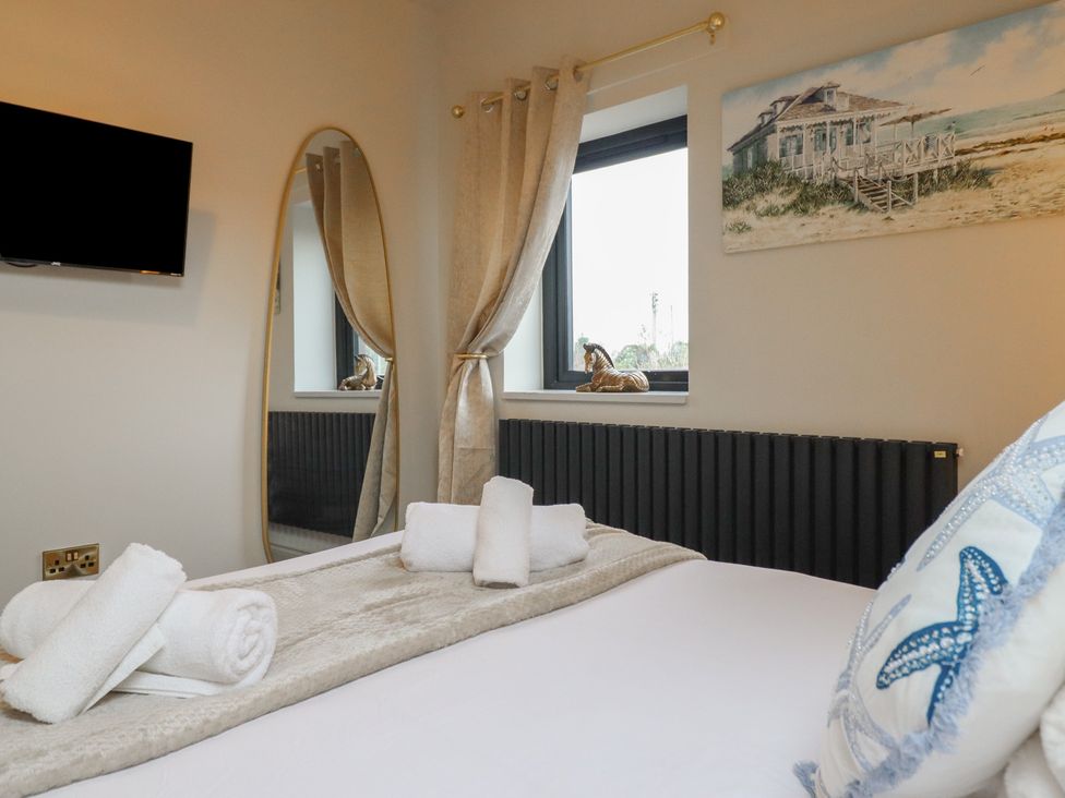 A bedroom with a bed, towels, and a television at Pistyll Ddu in Brynsiencyn near Llanfairpwllgwyngyll