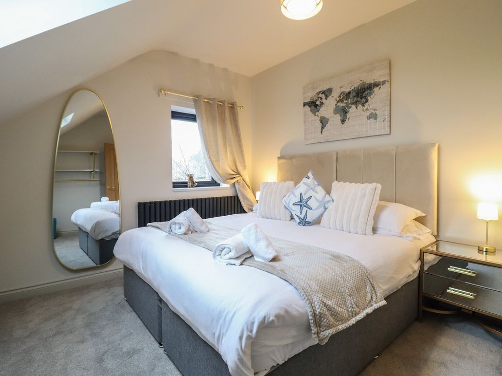 A bedroom with a bed and mirror at Pistyll Ddu, Brynsiencyn near Llanfairpwllgwyngyll