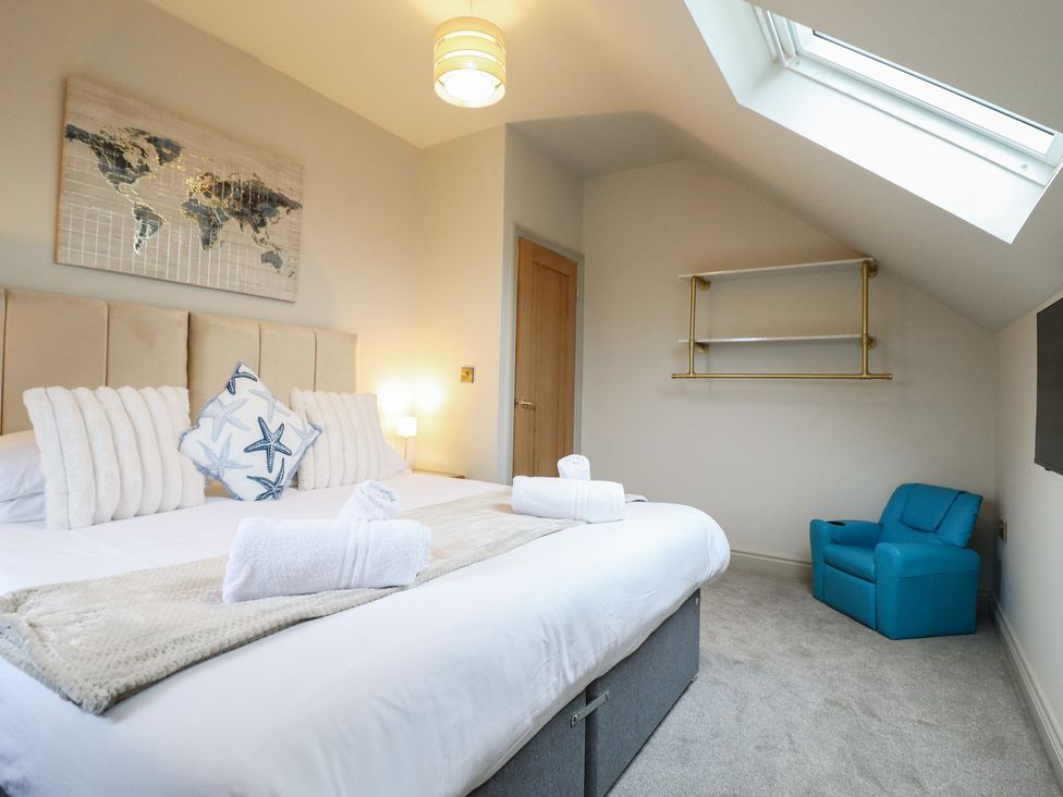 A bedroom with a bed and blue chair at Pistyll Ddu Brynsiencyn near Llanfairpwllgwyngyll