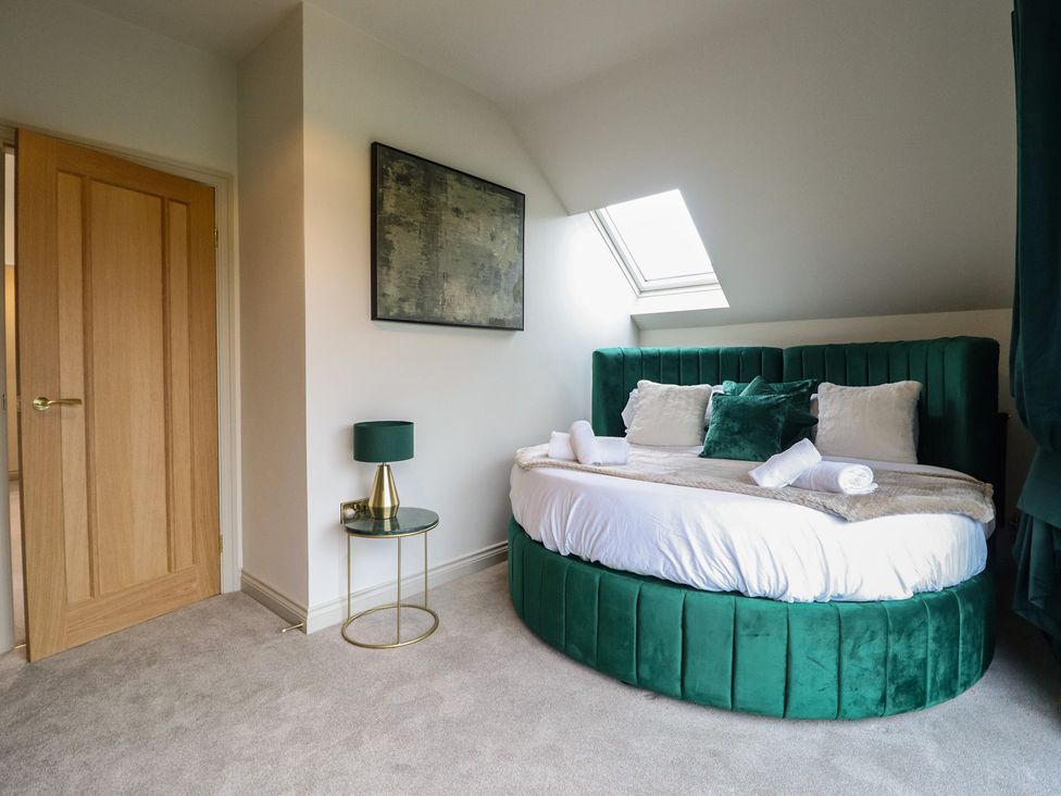 A bedroom with a round bed and a lamp at Pistyll Ddu in Brynsiencyn near Llanfairpwllgwyngyll