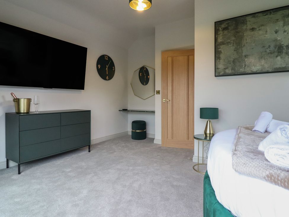 A bedroom with a television and clock above a dresser at Pistyll Ddu in Brynsiencyn near Llanfairpwllgwyngyll