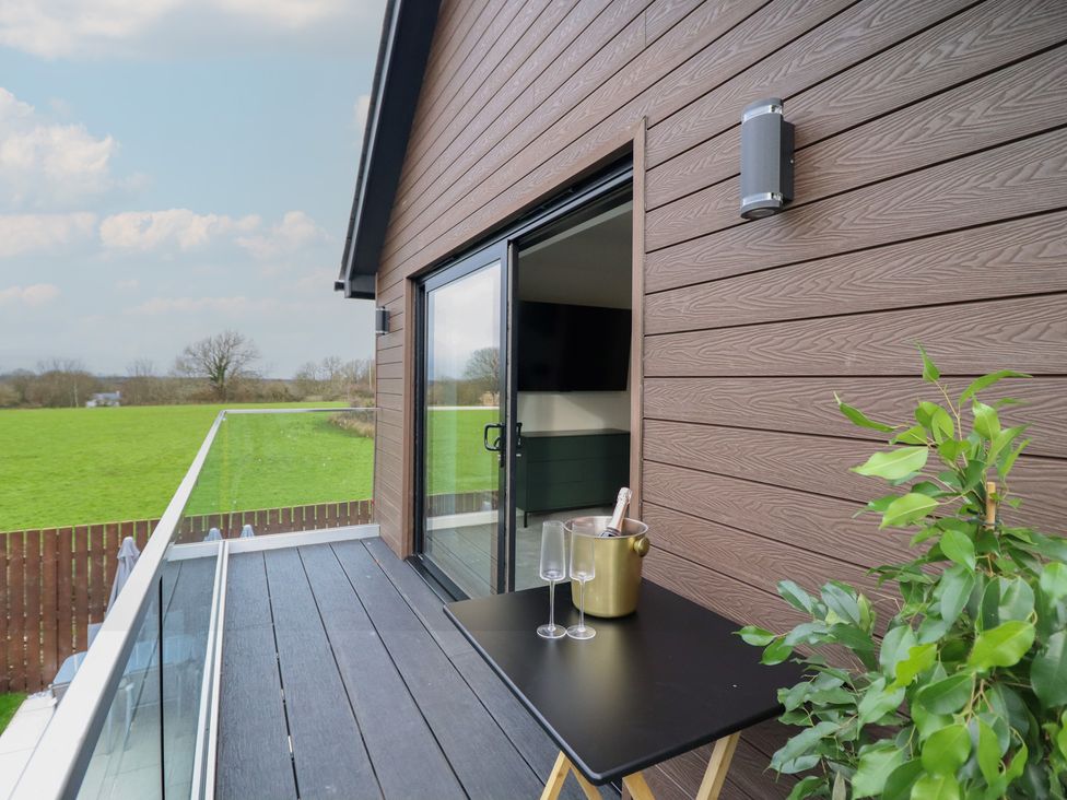 A balcony with a table and champagne bucket at Pistyll Ddu Brynsiencyn near Llanfairpwllgwyngyll