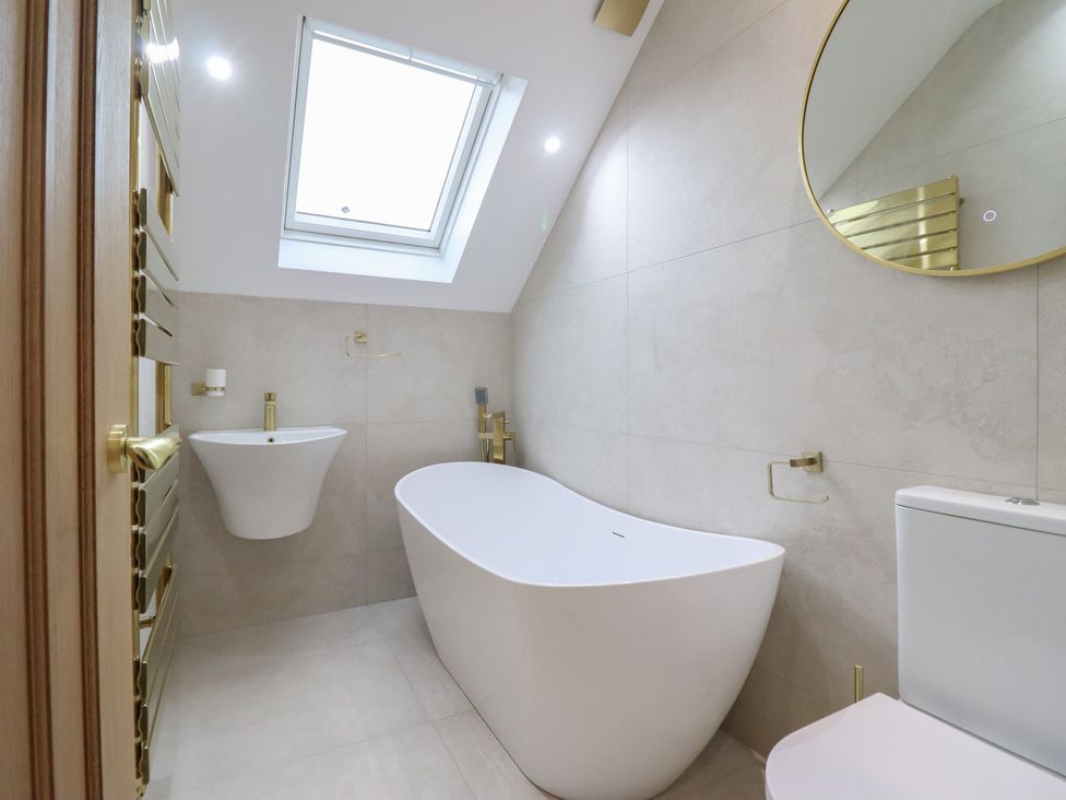 A bathroom with a bathtub, toilet, and sink at Pistyll Ddu in Brynsiencyn near Llanfairpwllgwyngyll