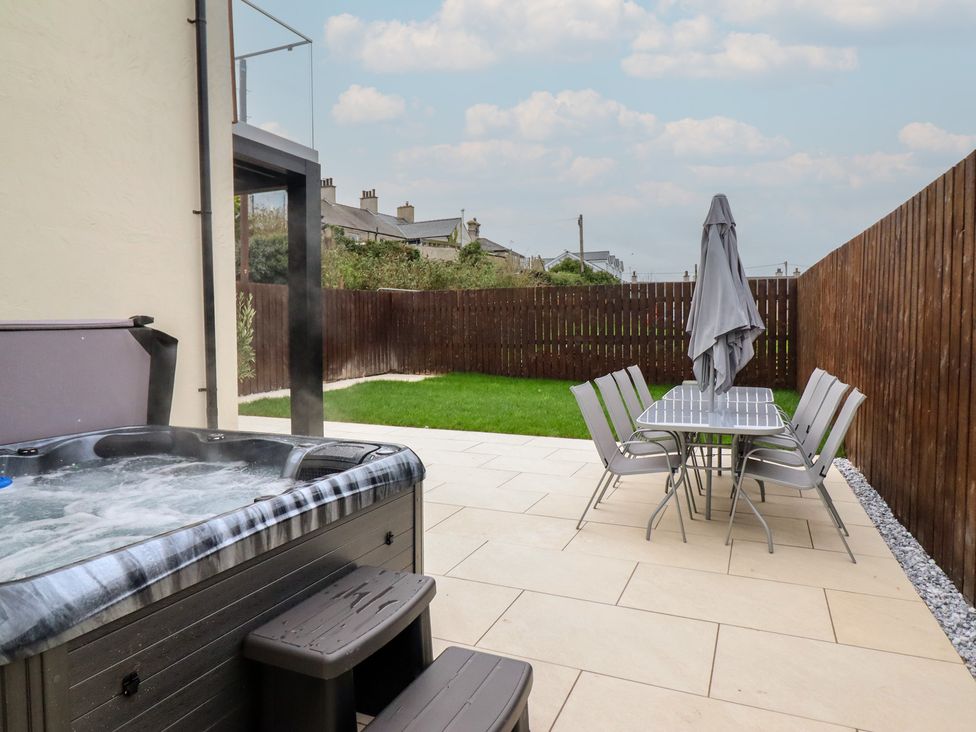 A garden with hot tub and dining set at Pistyll Ddu in Brynsiencyn near Llanfairpwllgwyngyll