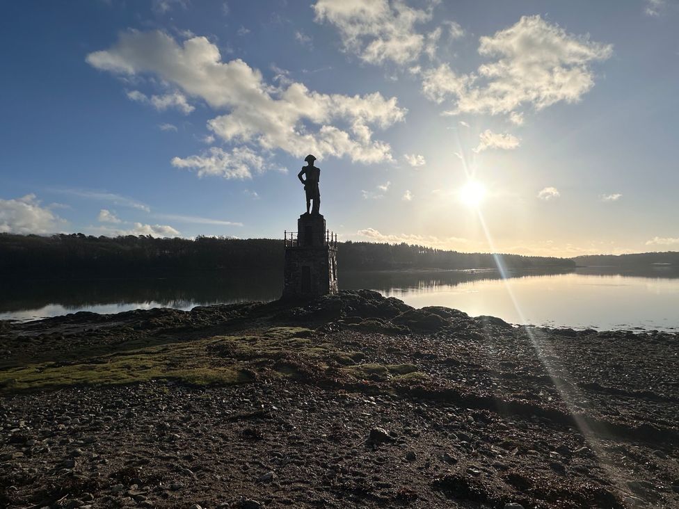A statue on a rocky shore during sunset at Pistyll Ddu in Llanfairpwllgwyngyll